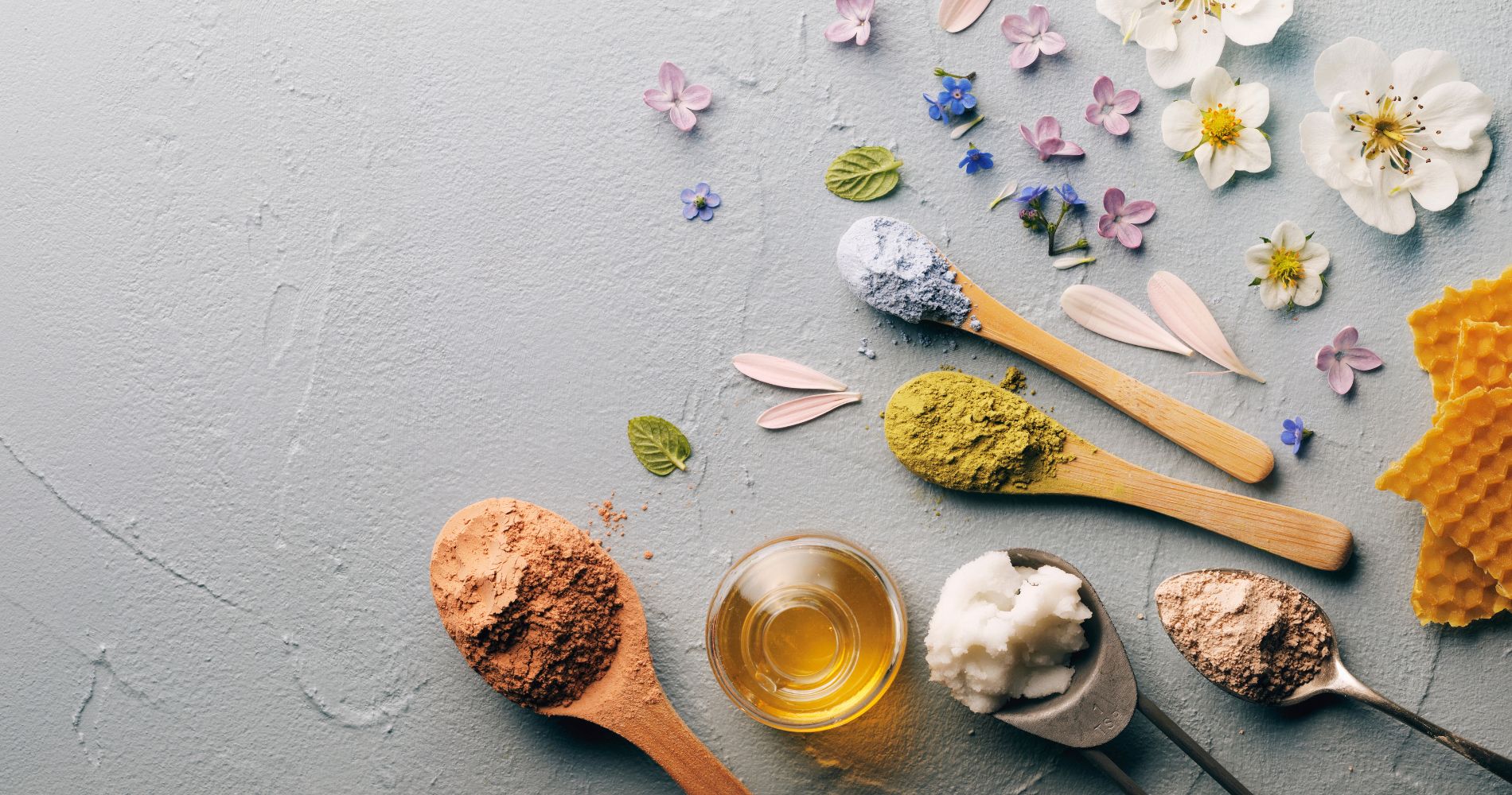 Naturalne składniki w kosmetykach – oleje roślinne, glinki i ekstrakty ziołowe na tle pastelowym.