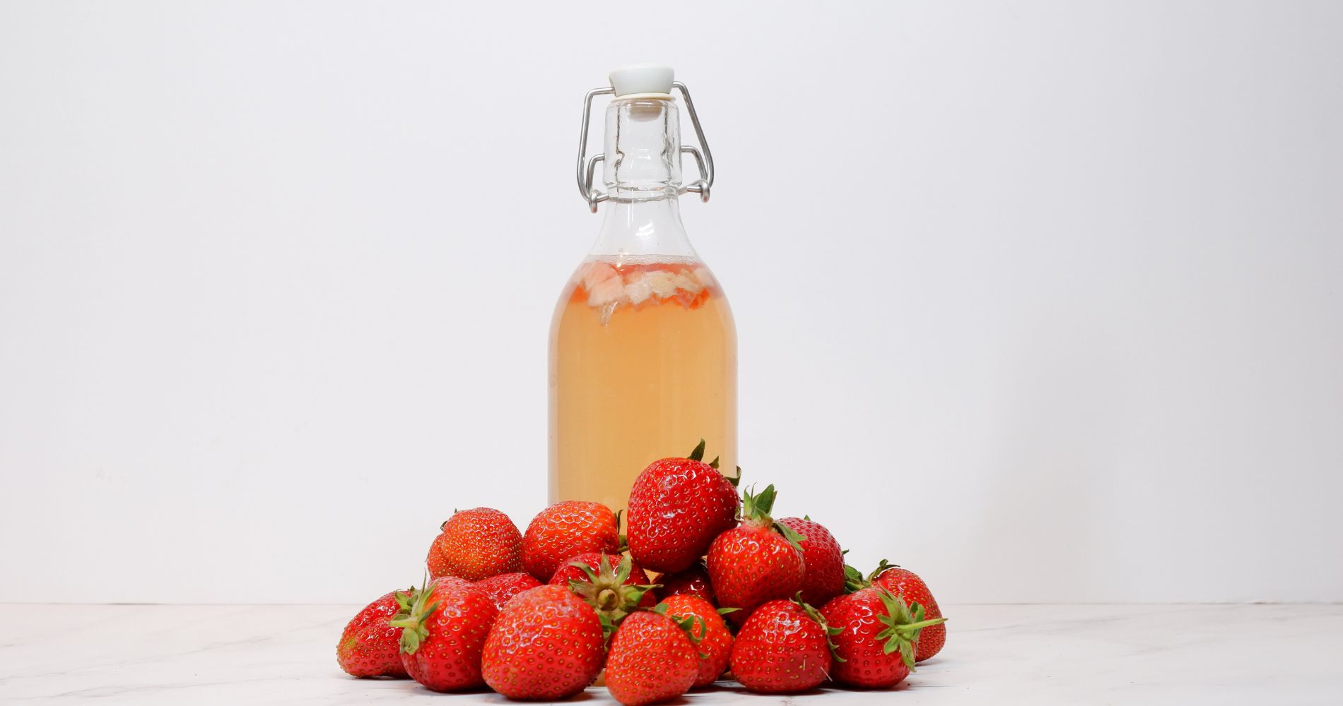 Butelka kombuchy z truskawkami – naturalny fermentowany napój.