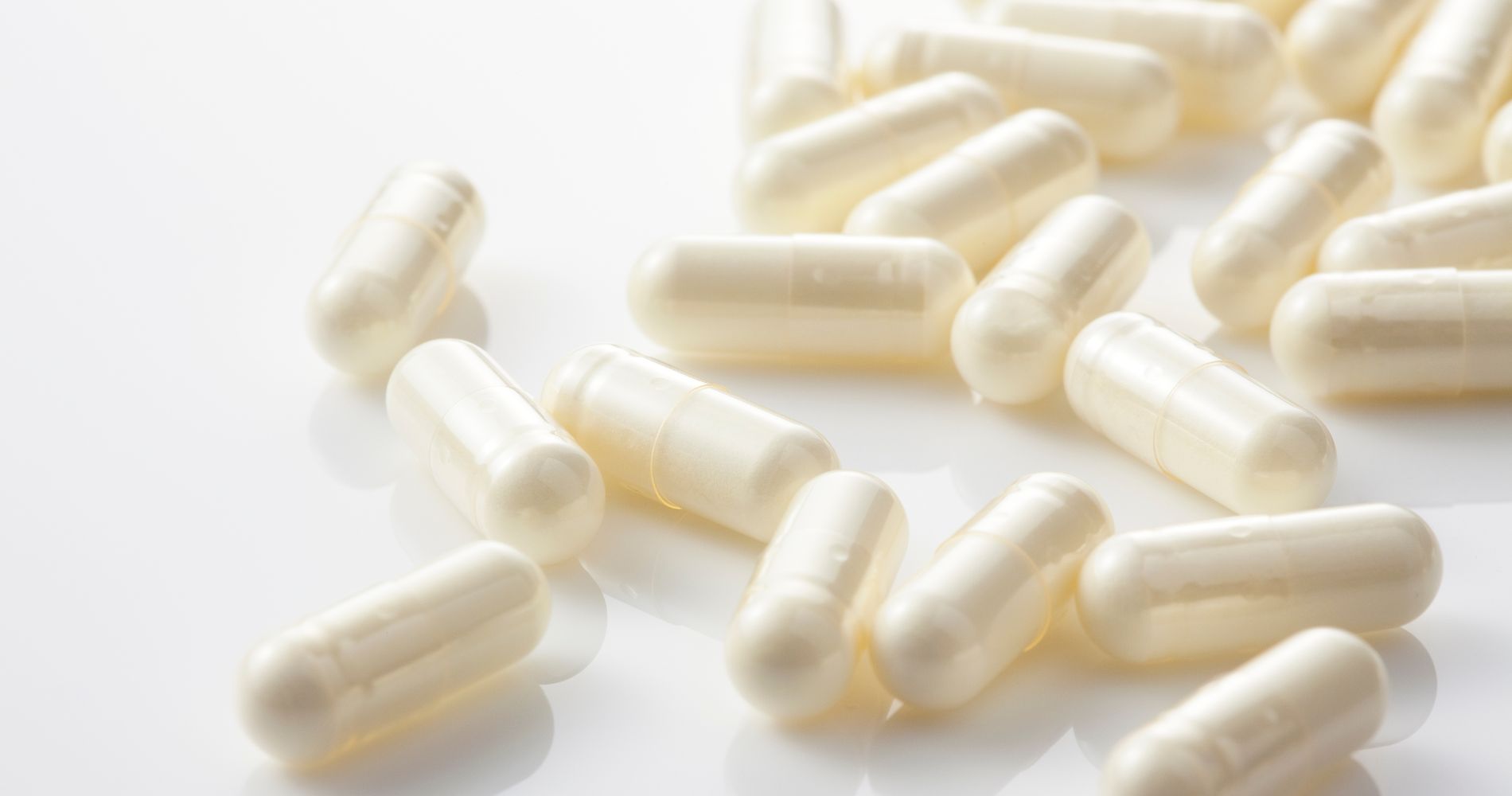 Białe kapsułki laktoferyny jako suplement wspierający odporność i ochronę przed infekcjami.