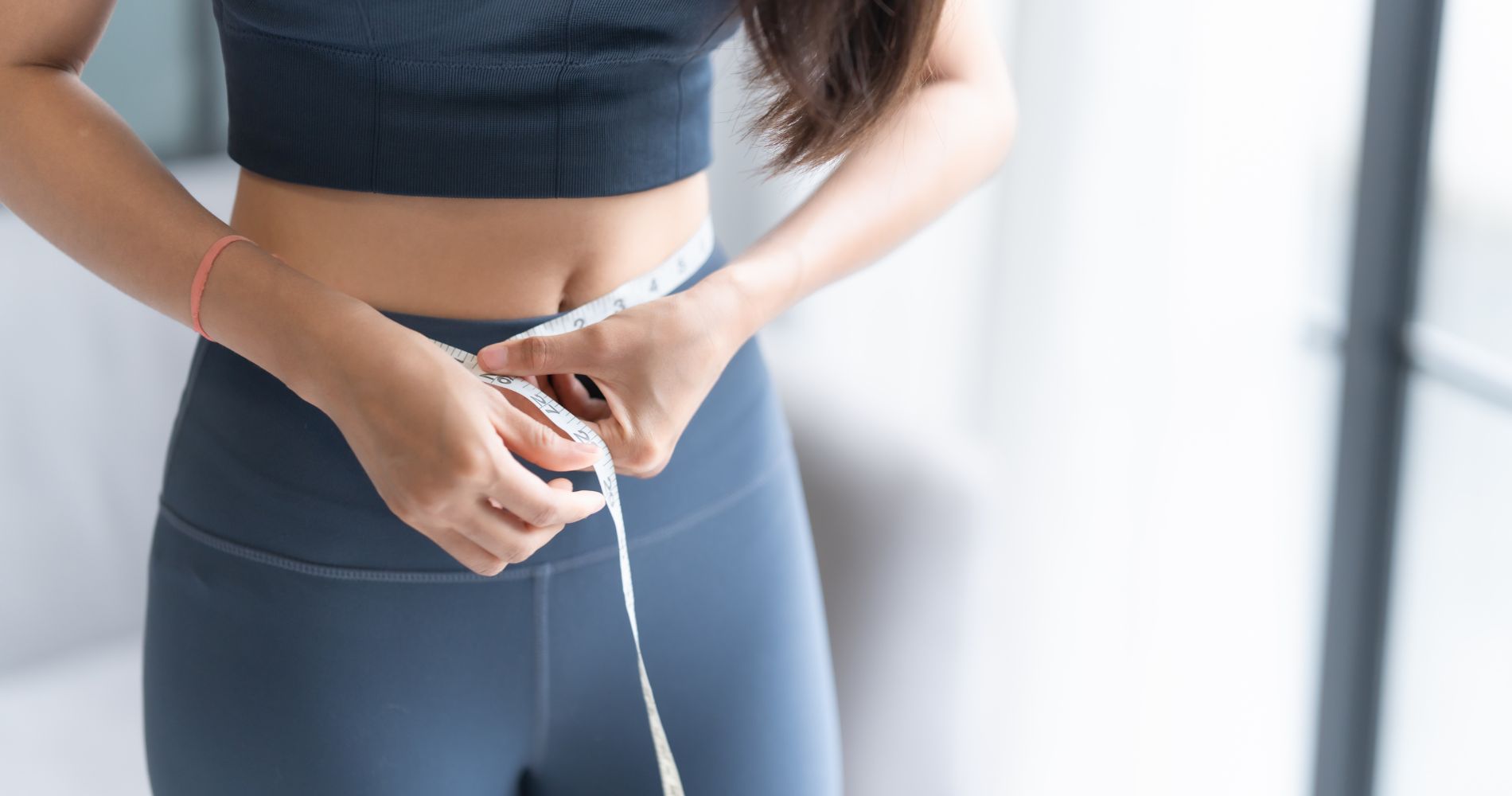 Osoba mierząca obwód talii podczas stosowania diety niskowęglowodanowej.