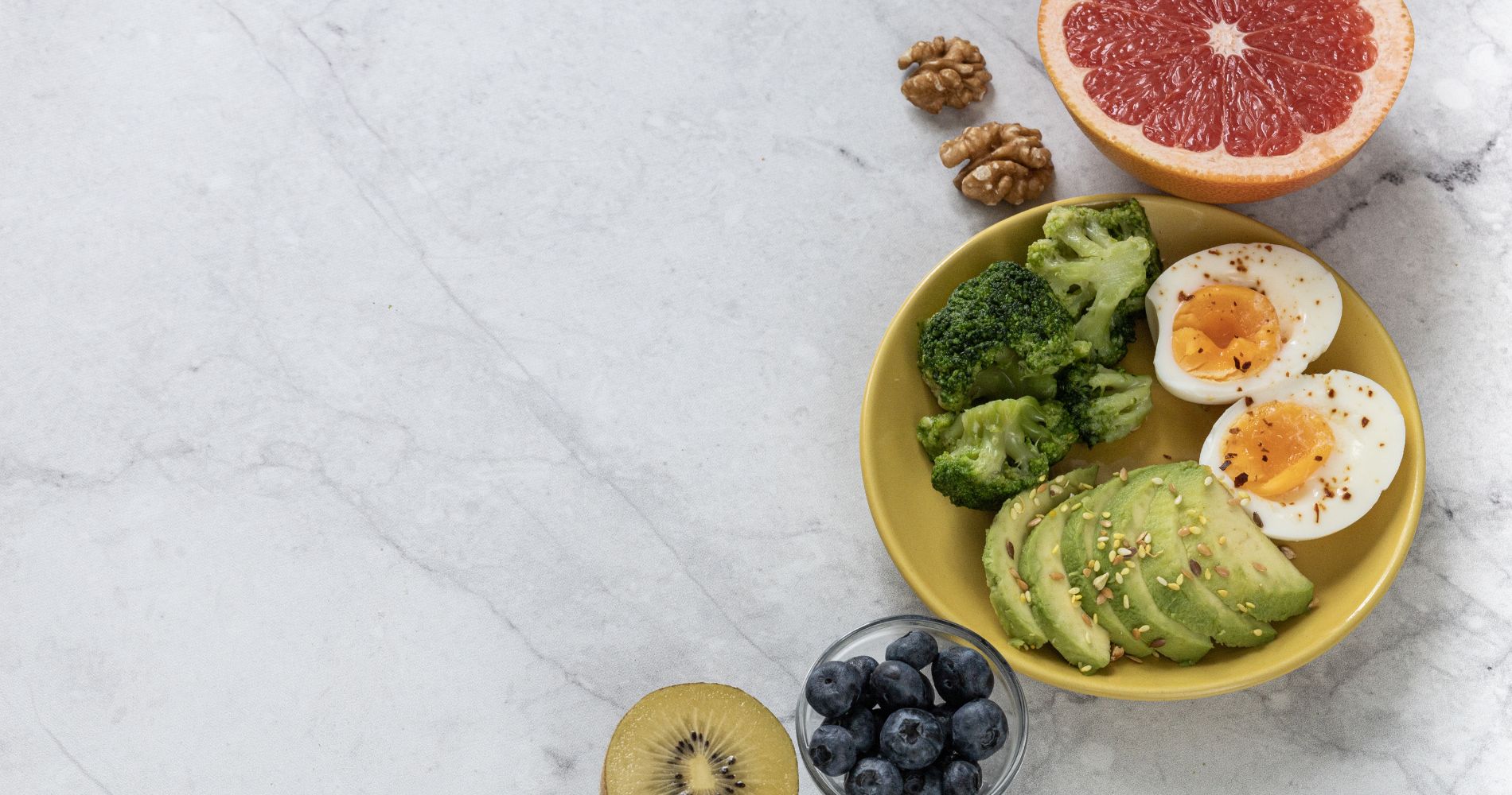 Zdrowy posiłek wspierający metabolizm – jajka, awokado, brokuły, owoce i orzechy na talerzu.