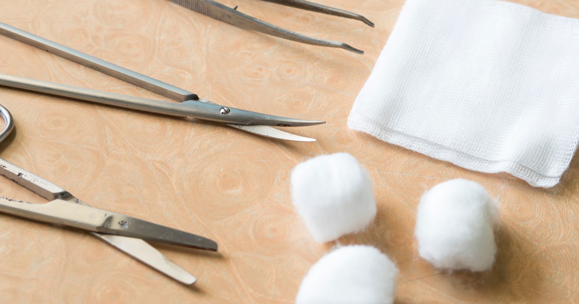 Narzędzia i materiały do pielęgnacji rany – jałowa gaza, nożyczki i waciki.