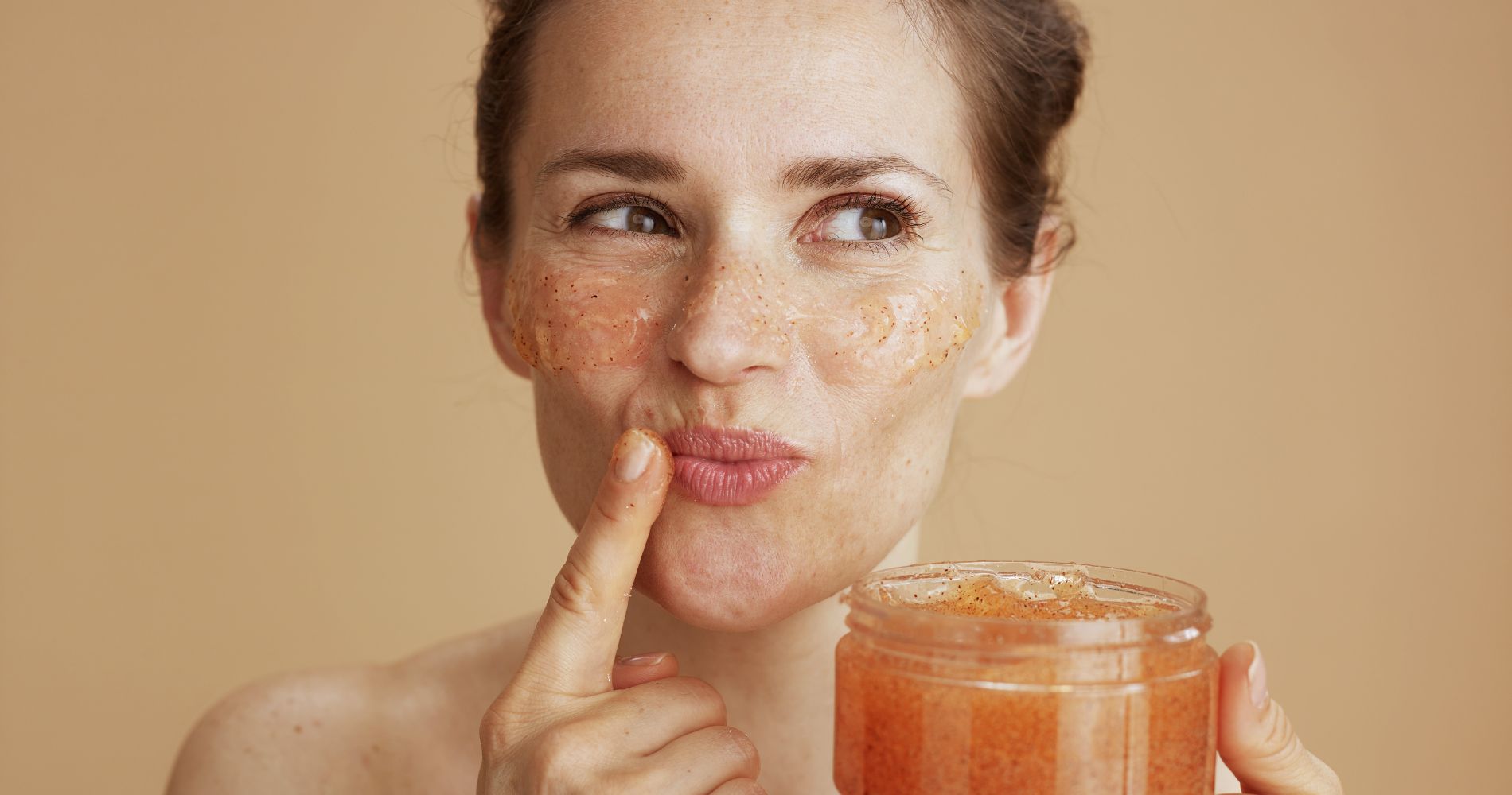 Peeling do twarzy – kobieta nakłada kosmetyk złuszczający na skórę.